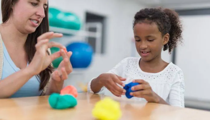 Therapist and young child working together with modeling clay during a developmental therapy session