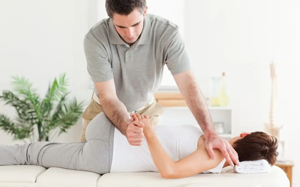 Therapist performing a hands-on manual therapy technique on a patient's shoulder and back