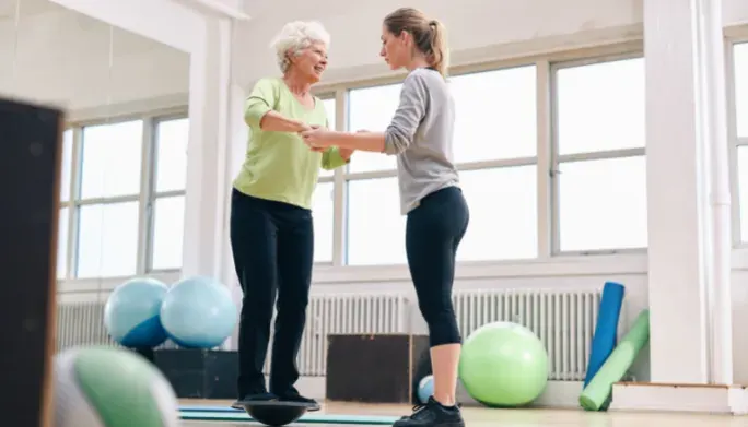 Physical therapist guiding a patient through a balance exercise on a trainer