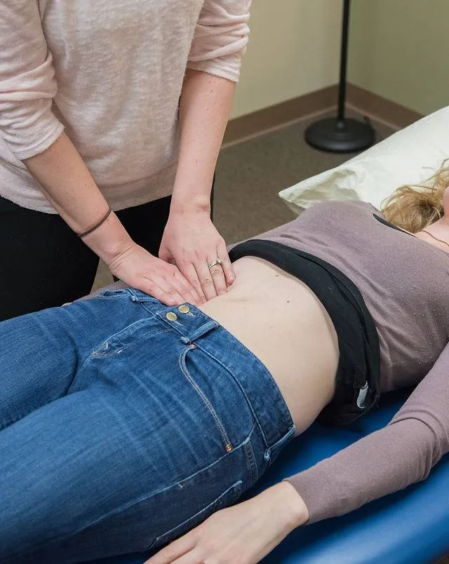 Physical therapist palpating a patient's abdomen during a pelvic floor evaluation