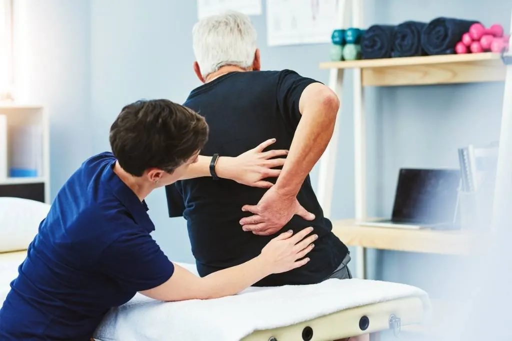 Physical therapist assessing a patient's lower back for chronic pain