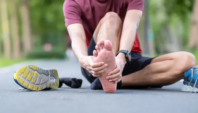 Runner holding their foot in pain outdoors