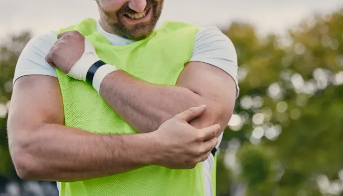 Person holding their forearm in pain outdoors