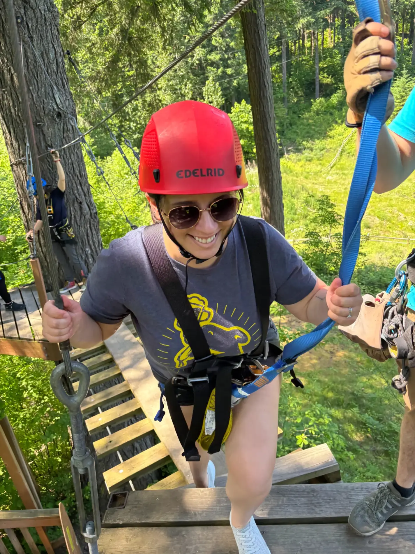 Dr. Claire Maederer harnessed up in a helmet and gloves on a treetop zipline course